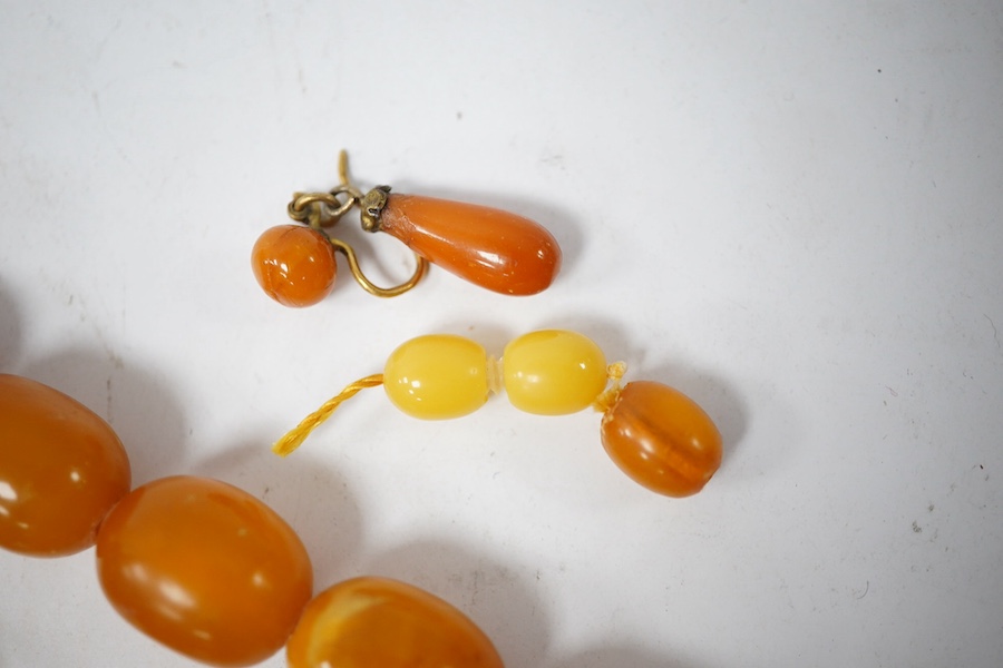 A single strand graduated oval amber bead necklace (a.f.), 90cm, gross weight 72 grams and three odd beads and an earring. Condition - poor